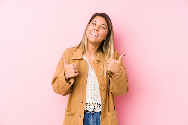 Young woman posing raising both thumbs up, smiling and confident