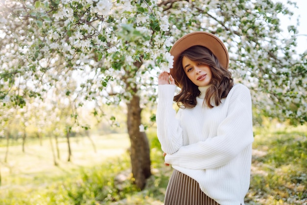 Young woman posing in spring blossom flowers in blooming garden Female beauty fashion