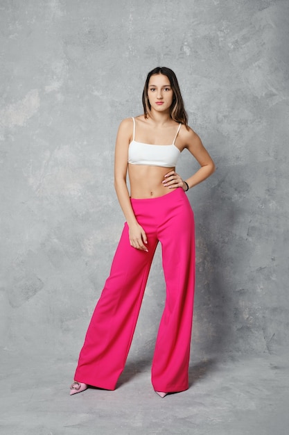 Young woman posing in wide cherry pink trousers and white tube top