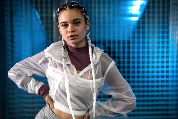 Young woman posing with her hands on her waist and looking at camera with background with blue light