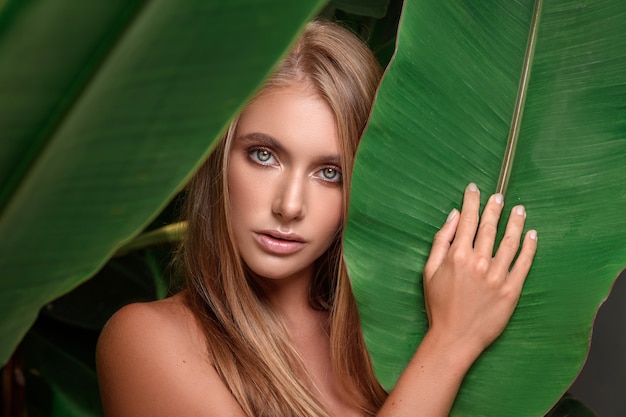 Young woman posing with tropical leaves