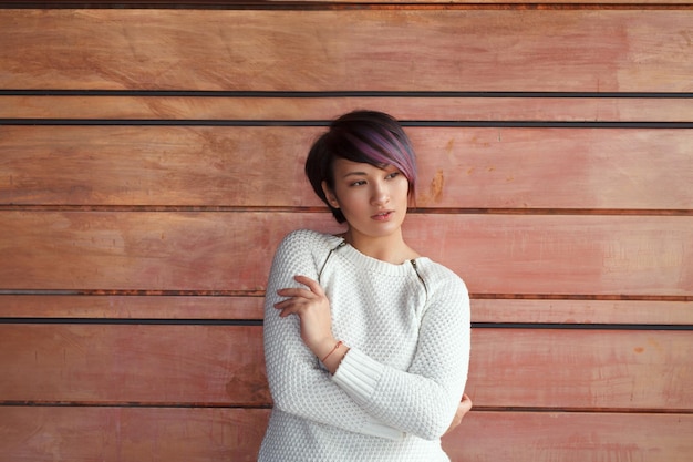 Young woman posing at wooden wall