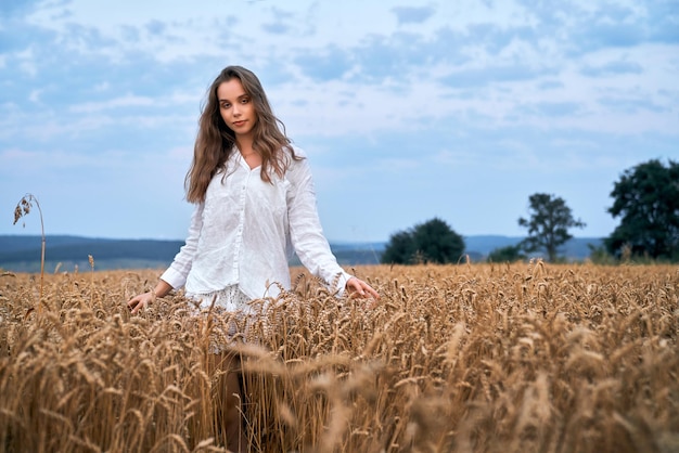 Giovane donna in posa sul campo di grano giallo