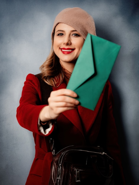 Young woman postman with green envelope