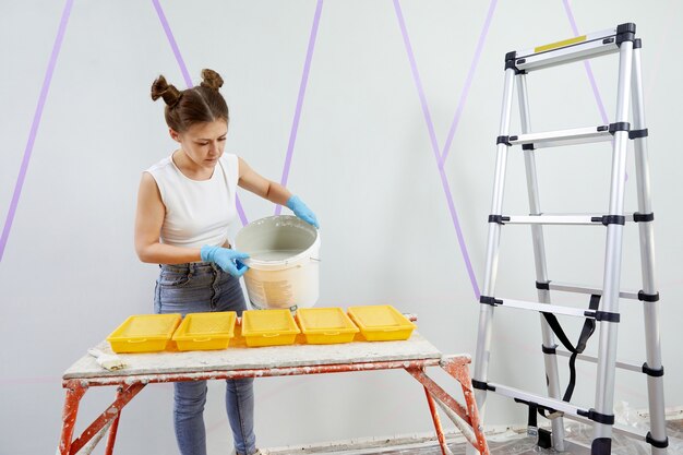 Young woman pouring paint into plastic paint tray