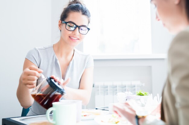 カフェでお茶を注ぐ若い女性