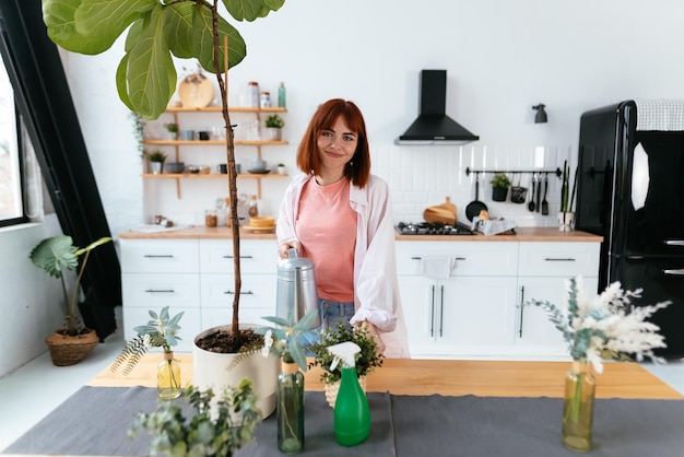 Young woman pouring water in flower pot with indoor houseplant from watering can