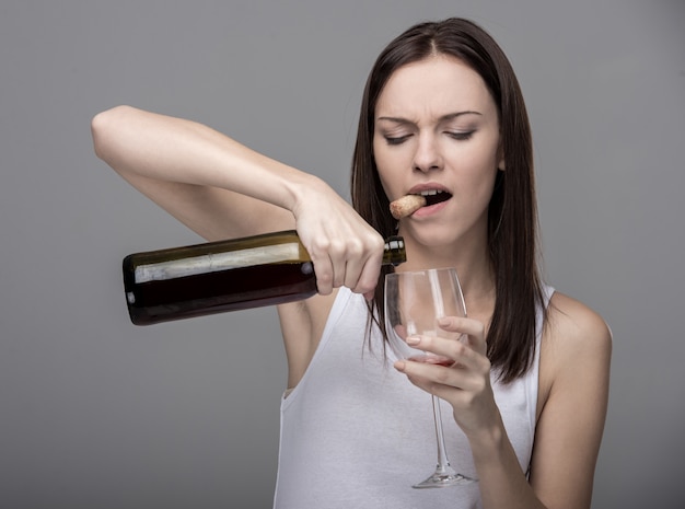 Young woman pours wine into a glass.