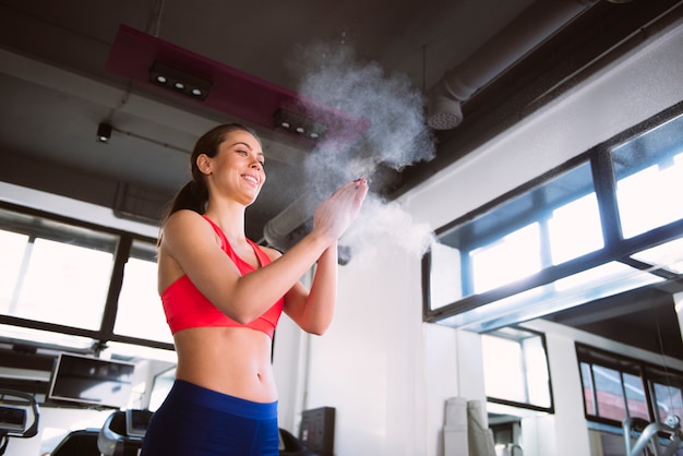 Young woman powder hands before exercise in the gym