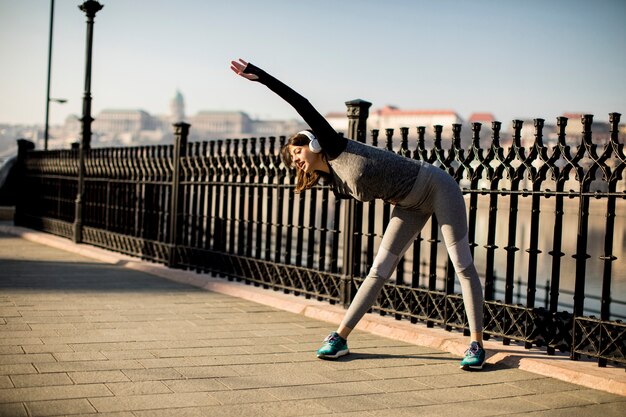 Young woman practices stretching after jogging outdoor