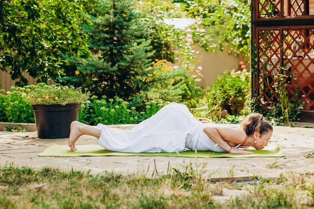 Young woman practices yoga in the garden Surya namaskar Fourpoint pose Ashtanga Namaskar or greeting with eight body parts