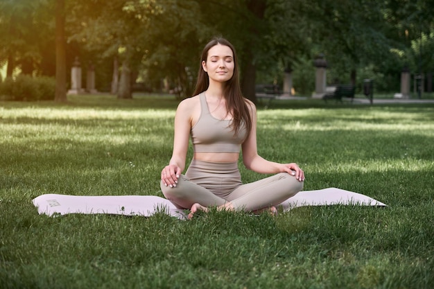 A young woman practices yoga in a public park on a warm summer day