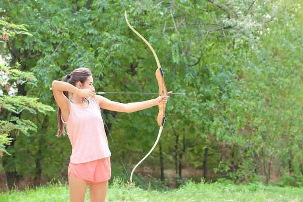 Young woman practicing archery outdoors