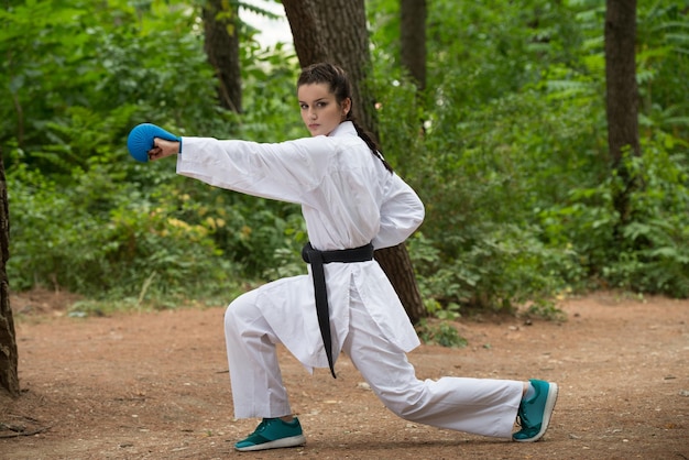 Young Woman Practicing Her Karate Moves in Wooded Forest Area  White Kimono  Black Belt