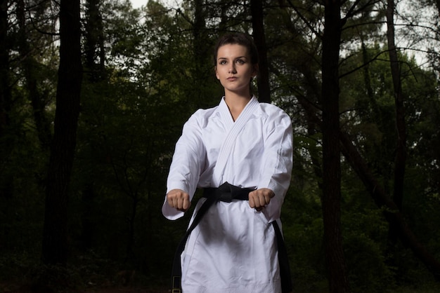 Young Woman Practicing Her Karate Moves in Wooded Forest Area  White Kimono  Black Belt