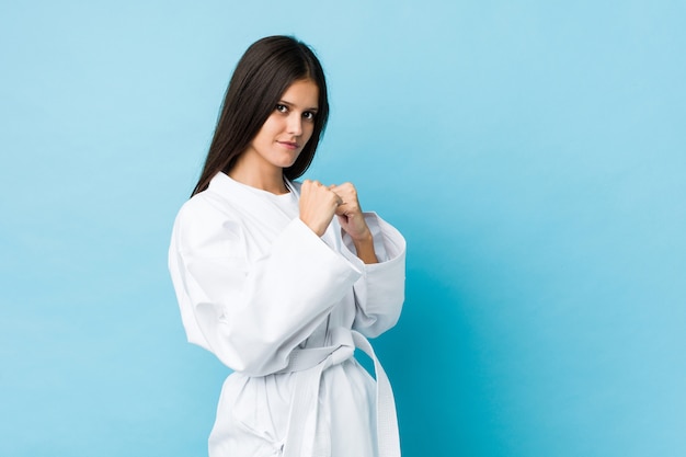 Young woman practicing karate isolated on a blue wall