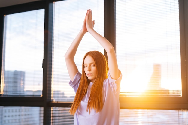 Giovane donna che pratica asana di yoga che alza le mani in namaste mudra