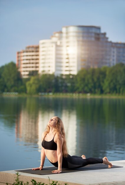 Giovane donna che pratica yoga nel lago della città