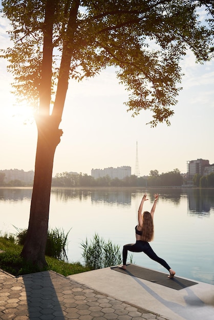 Young woman practicing yoga at city lake