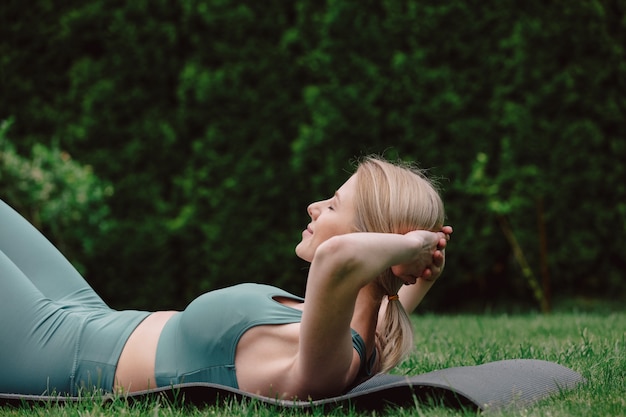 Young woman practicing yoga on the grass in the garden