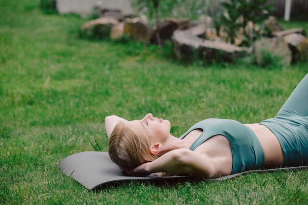 Young woman practicing yoga on the grass in the garden