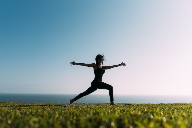 Photo young woman practicing yoga on grass outdoors spreading her arms and disheveled