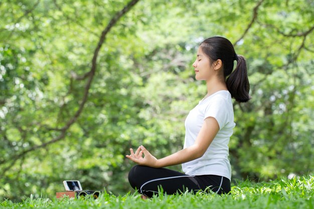 Giovane donna che pratica lo yoga nella natura, donna asiatica sta praticando lo yoga nel parco cittadino