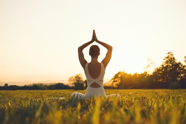 Young woman practicing yoga on nature Girl meditating outdoors