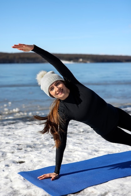 Foto giovane donna che pratica yoga all'aperto durante l'inverno sulla spiaggia