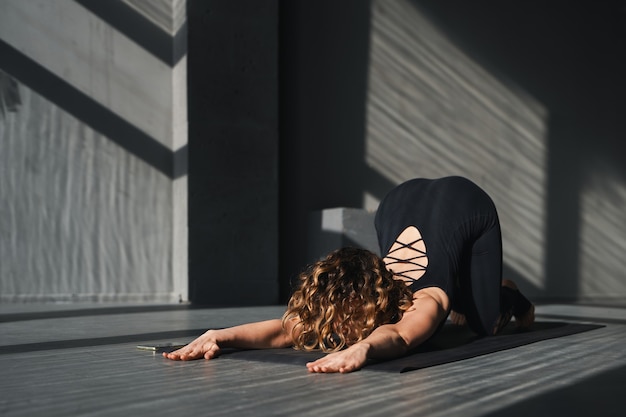 Giovane donna che pratica lo yoga pone in uno sfondo urbano in giornata di sole