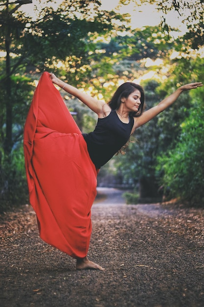 Foto giovane donna che pratica yoga sulla strada nella foresta