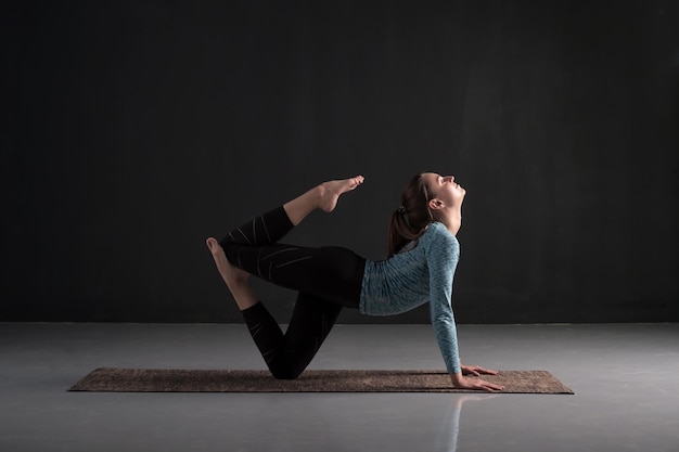 Young woman practicing yoga working out Indoor full length