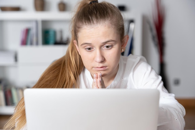 Young woman praying and looking to laptop