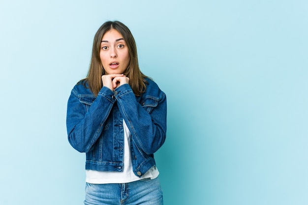 Young woman praying for luck, amazed and opening mouth looking to front