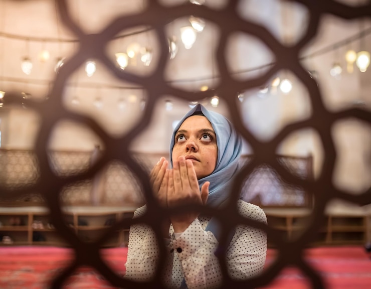 Photo 窓のフェンスから見えるモスクで祈っている若い女性