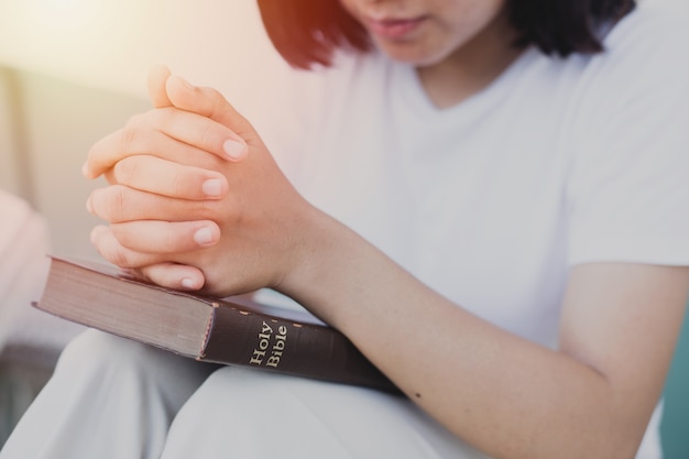 Young woman praying with the holy bible