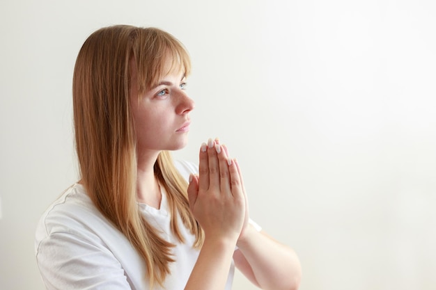 Фото Молодая женщина молится, произносит молитву на белом фоне