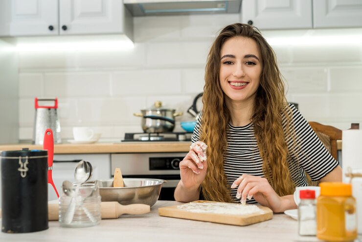 Photo young woman prepare delicious food knead flour on kitchen table. cooking food with different ingredient
