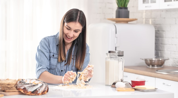 Young woman prepares dough for homemade cakes in a spacious bright kitchen.