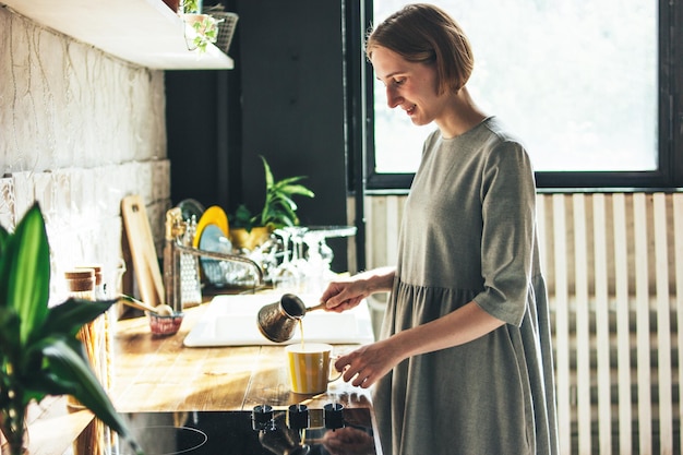 young woman preparing coffee in kitchen at home