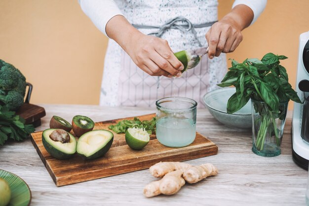 Young woman preparing detox juice with cold pressed extractor machine - Girl making smoothie with green vegetables and fruit -