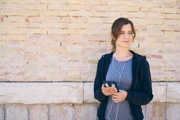 Young woman preparing to exercise, using mobile phone with headphones