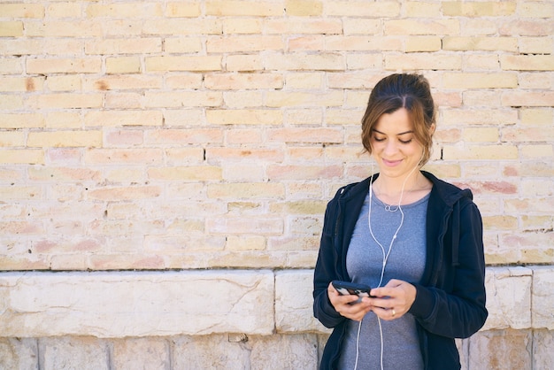 Young woman preparing to exercise, using mobile phone with headphones