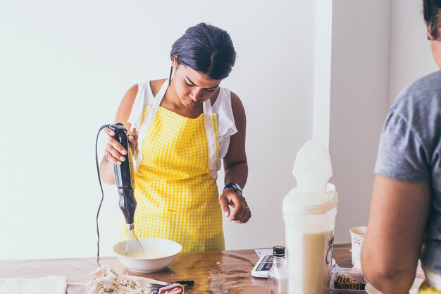 写真 テーブルに立って食べ物を準備する若い女性