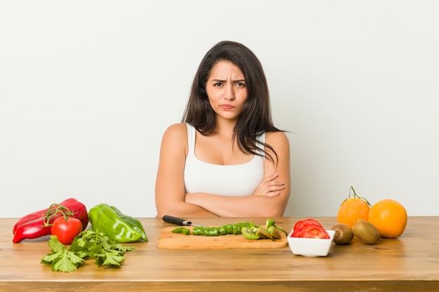 Young woman preparing a healthy meal frowning face in displeasure, keeps arms folded.