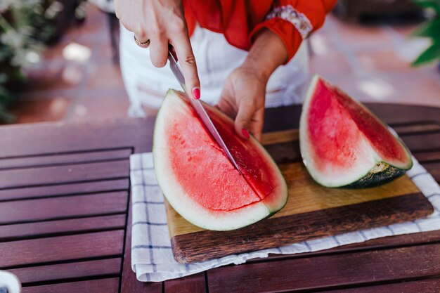 Young woman preparing a healthy recipe of diverse fruits,\
watermelon, orange and blackberries. using a mixer. homemade,\
indoors, healthy lifestyle