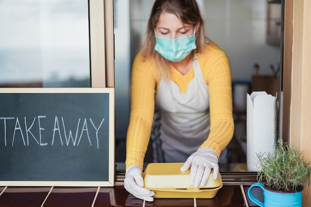 Giovane donna che prepara fast food da asporto durante l'epidemia di coronavirus