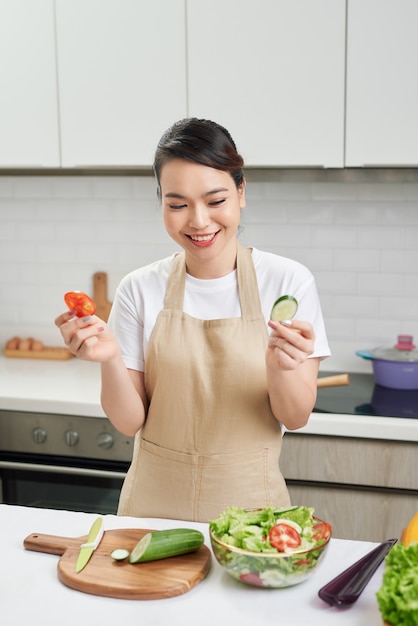 キッチンで野菜サラダを準備する若い女性