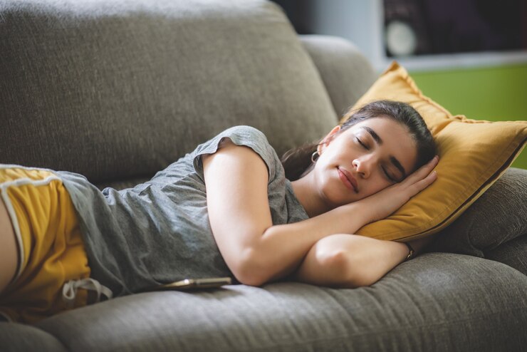 Photo 居心地の良いソファで安らかに暮らし、安らかに眠る若い女性のかわいい女の子、ソファを楽しんで、屋内のアパートの部屋でリラックスして横たわって、快適な笑顔