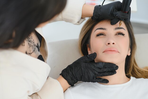 Young woman during procedure of permanent eyebrow makeup